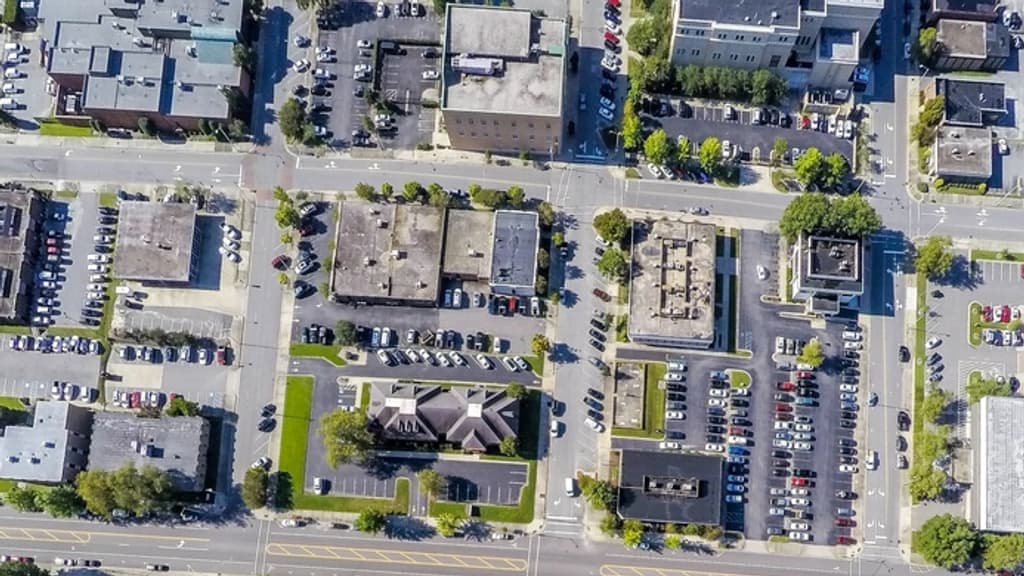 Aerial photograph looking straight down on a commercial block: flat-roofed buildings standing on separate lots, each with its own parking apron.