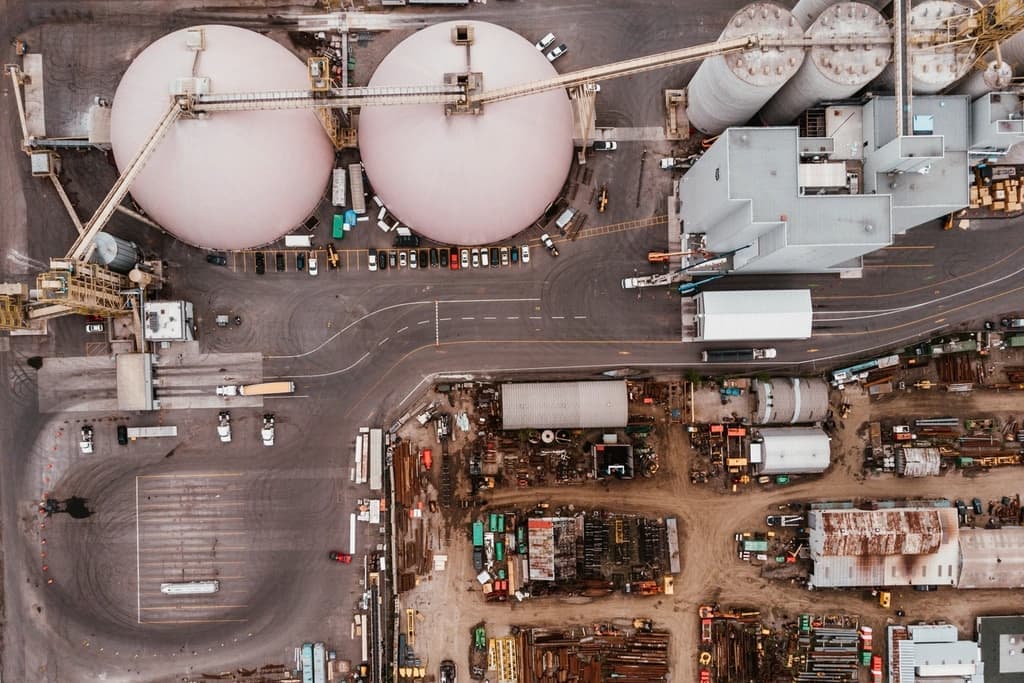 Aerial photograph looking straight down on an industrial yard with storage domes, sheds, and stacked material.